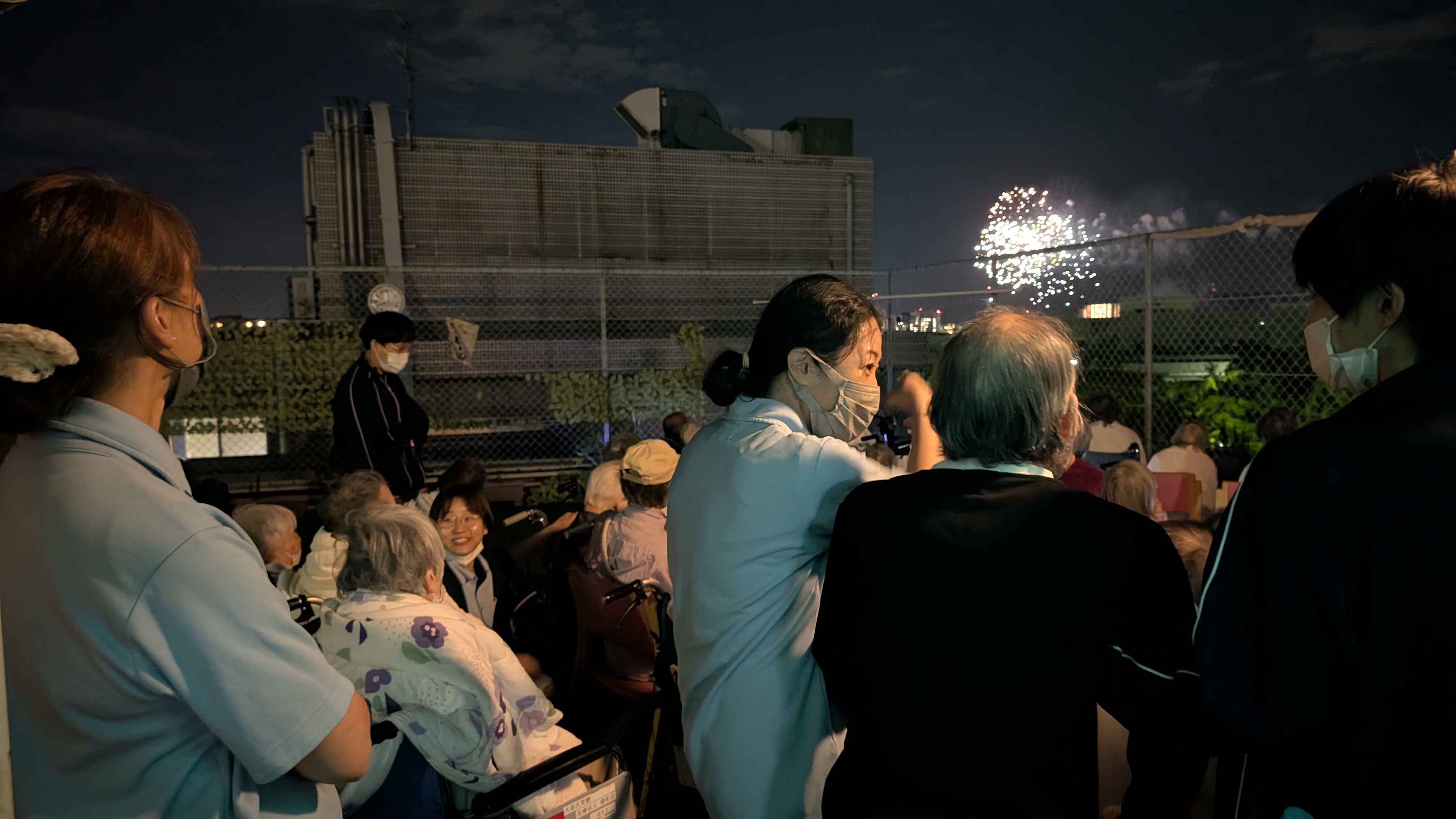 老健利用者さんと職員が一緒に花火を見る様子